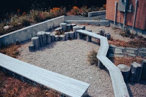 Rustic wooden benches and logs in a simple outdoor gravel yard setting.